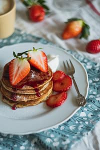 tavola con piattino di pancakes cacao e fragole